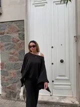 Blusa de lanilla color beige, con diseño de un solo hombro y corte holgado tipo capa.