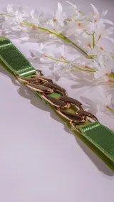 Cinto elastizado color verde con aplique de cadena dorada.