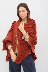 Chal de lana color marrón con diseño envolvente, decorado con volados aplicados en toda la superficie que aportan textura y movimiento.