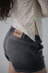 Mini short de jean tiro bajo color gris oscuro, con bolsillos delanteros y traseros.