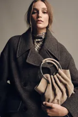 Bolso tipo saca de serraje color beige con doble asa rígida asimétrica y asa bandolera extraíble. Incluye cartera con bolsillo extraíble.