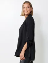 Blusa de tejido piqué color fucsia, con escote en V y pliegue central delantero. Presenta mangas largas con sistema de ajuste mediante presilla y botón, y tajos laterales en el ruedo.