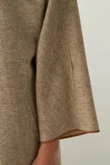 Tapado de largo medio abierto con cuello, confeccionado en lana fina sin teñir con detalles de terminación envivados en los bordes y mangas tres cuartos.