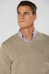 Suéter de tejido fino color azul marino, con cuello en V y manga larga. Presenta un pequeño logo bordado en el pecho.