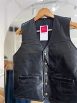 Chaleco negro de cuero con diseño de paneles geométricos y botones dorados.