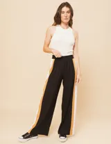 Pantalón palazzo color beige con cintura elastizada y dos franjas verticales en los laterales, una plateada y otra blanca.