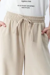 Pantalón beige de corte palazzo con cintura elastizada y cordón ajustable.