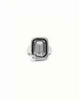 Anillo plateado con un cristal facetado rectangular de color azul oscuro. El diseño está inspirado en un clavo.