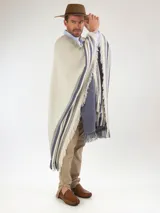 Poncho de hilo color crudo, con diseño de rayas azules y flecos en los bordes. Cuenta con un escudo bordado en la parte posterior.