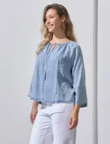 Blusa celeste de lyocell con cuello a la base y escote en V con lazo de ajuste. Manga larga amplia.