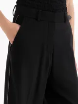 Pantalón sastre color negro de corte recto y tiro alto, confeccionado en mezcla de viscosa y elastano. Presenta bolsillos laterales, presillas para cinto y un delicado vivo decorativo a lo largo de los laterales.