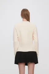 Saco negro de punto, con cuello redondo a la base, manga larga y cierre frontal con botones.