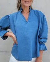 Blusa de algodón con cuello mao y volados, mangas largas con puños elásticos y corte holgado.