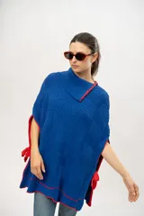 Capa tipo poncho tejido de punto color azul con detalles en rojo.
