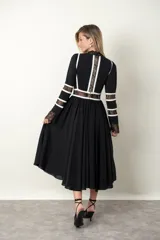 Vestido midi blanco con detalles de encaje y vivos negros. Tiene cuello mao, mangas largas con puños de encaje y falda amplia con tul de armar.