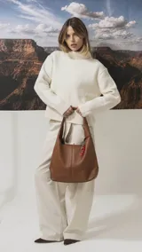 Cartera tipo hobo de cuero sintético color tostado, con diseño de hombro, costuras verticales decorativas y monedero pequeño extraíble a tono.