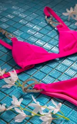 Conjunto de bikini fucsia con corpiño triangular y bombacha clásica con argollas plateadas con strass en los laterales.