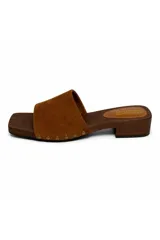 Zueco de inspiración artesanal marca Daniel Cassin, con base efecto madera y taco bajo. Presenta una capellada ancha de color negro con detalles de tachas metálicas doradas en los laterales.