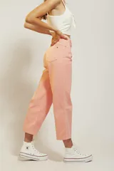 Pantalón de jean color amarillo pastel, de corte recto y tiro medio, con diseño de cinco bolsillos y cierre frontal con botón y cremallera.