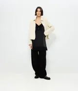Pantalón de sastrería corte barrel, color negro, con cintura de cierre desplazado, pliegues delanteros y piernas anchas.