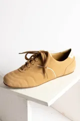 Zapatillas acordonadas color beige con detalles en blanco.