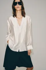 Camisa fluida Zara Woman Collection confeccionada en hilatura con mezcla de lyocell, en color amarillo claro. Presenta escote en pico, manga larga con puño ancho y cierre frontal oculto.