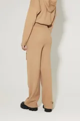 Pantalón tejido color beige, de calce relaxed, con elástico en la cintura, lazo incorporado y bolsillos delanteros.
