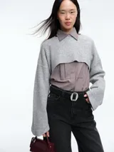 Sweater de punto en color gris, con diseño crop de mangas largas y cuello bote. Presenta una textura acanalada y un corte moderno que permite superposiciones.