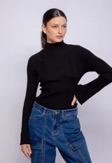 Polera negra de símil cuero, con cuello alto y mangas largas acampanadas.