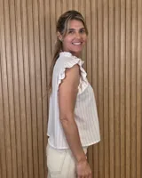 Musculosa a rayas verdes y blancas, con cuello alto fruncido, cierre frontal con botones y volados en los hombros.