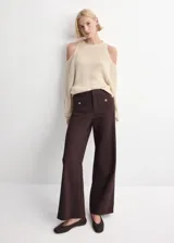Pantalón de vestir color marrón, de corte ancho y tiro medio. Presenta bolsillos frontales tipo parche con solapa y detalle de botón metálico en cada uno.
