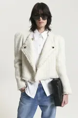 Saco corto de tweed color crudo con solapas con flecos y botones dorados.