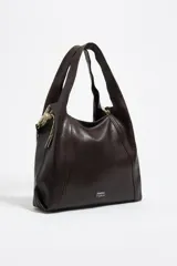 Bolso de mano grande de estructura blanda confeccionado en piel vacuna color marrón oscuro. Presenta asas fijas, cierre de cordón ajustable en los laterales y logo metálico de la marca en la parte frontal.