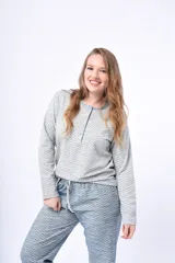 Pijama de dos piezas compuesto por una remera de manga larga con cuello redondo y cartera de botones, y un pantalón largo de corte recto. Ambas prendas presentan un estampado geométrico sutil en tonos gris y azul.