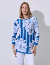 Buzo tejido en hilado fino, con cuello redondo y mangas 3/4. Presenta un estampado floral en tonos azules sobre un fondo a rayas verticales en diferentes tonos de azul.