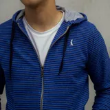 Campera con capucha azul a rayas horizontales negras, con cierre frontal y bolsillos laterales.