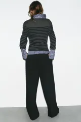 Pantalón de tiro medio con corte recto y holgado. Presenta pinzas en el delantero, trabillas para cinturón y cierre frontal con cremallera, botón y gancho metálico. Incluye bolsillos laterales y detalle de tapetas en la parte trasera.