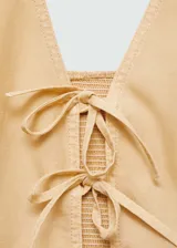 Top corto de cuello halter con cierre frontal mediante lazos decorativos. Presenta un diseño ajustado y sin mangas, confeccionado en una mezcla de fibras naturales.