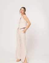 Pantalón negro de lino, tiro alto, corte palazo, con elástico en la pretina trasera, cierre delantero y broche interno. Tiene bolsillos laterales, dobladillo invisible y tajos a los costados.