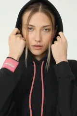 Buzo hoodie negro oversize de rústico, con capucha y cordones de ajuste color salmón y verde. Etiqueta con logo Basset 00'S en la manga derecha.