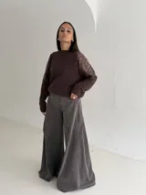 Sweater negro de tejido de punto con cuello redondo y mangas largas. Presenta detalles de transparencias y apliques bordados con pedrería en la parte superior de las mangas.