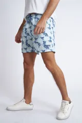 Short de baño con cintura elástica y cordón ajustable, confeccionado en tela ligera de secado rápido. Presenta un estampado botánico integral en tonos amarillos, blancos y azules, con dos bolsillos delanteros y uno posterior.
