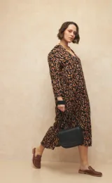 Vestido midi con estampado animal print en tonos marrones y negros, escote en V, cuello camisero y mangas tres cuartos. Cuenta con aberturas laterales.