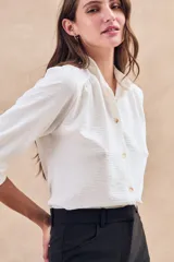 Blusa negra con cuello mao, calce al cuerpo y mangas 3/4 con puños abotonados. Cierre frontal con botones.