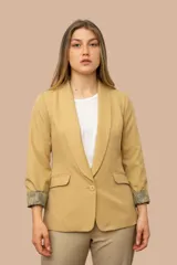 Blazer color camel con solapa entera, cierre de un botón y dos bolsillos delanteros con solapa. Forro estampado con diseño paisley en tonos grises y celestes, visible en los puños al doblarlos.