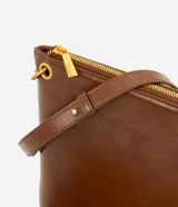 Bolso tipo postman de tamaño mediano en color marrón, con cierre superior y correa ajustable. Presenta un diseño rectangular con múltiples borlas largas en la parte inferior con estampado animal print.