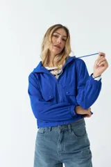 Campera deportiva corta color azul eléctrico, con capucha ajustable, cierre frontal y bolsillos con solapa y botón.