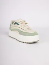 Zapatilla de plataforma con diseño de recortes en tonos blanco, beige y detalles metalizados plateados. Cuenta con suela texturizada y cierre mediante cordones.