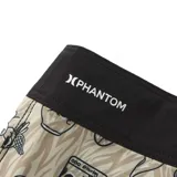 Bermuda de baño beige con estampado de calaveras, flores y rayas. Tiene cintura negra con cordón ajustable y dos bandas negras horizontales en la pierna izquierda.