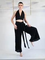 Conjunto de top halter y pantalón palazzo negros con textura y pequeños apliques brillantes. El top se ata al cuello y el pantalón tiene lazo en la cintura.